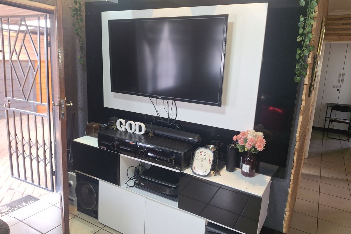 Living area featuring a modern built-in media console with high-contrast cabinetry and tiled flooring, providing a functional entertainment space.