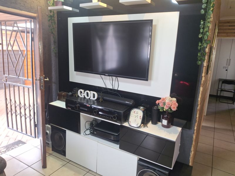Living area featuring a modern built-in media console with high-contrast cabinetry and tiled flooring, providing a functional entertainment space.