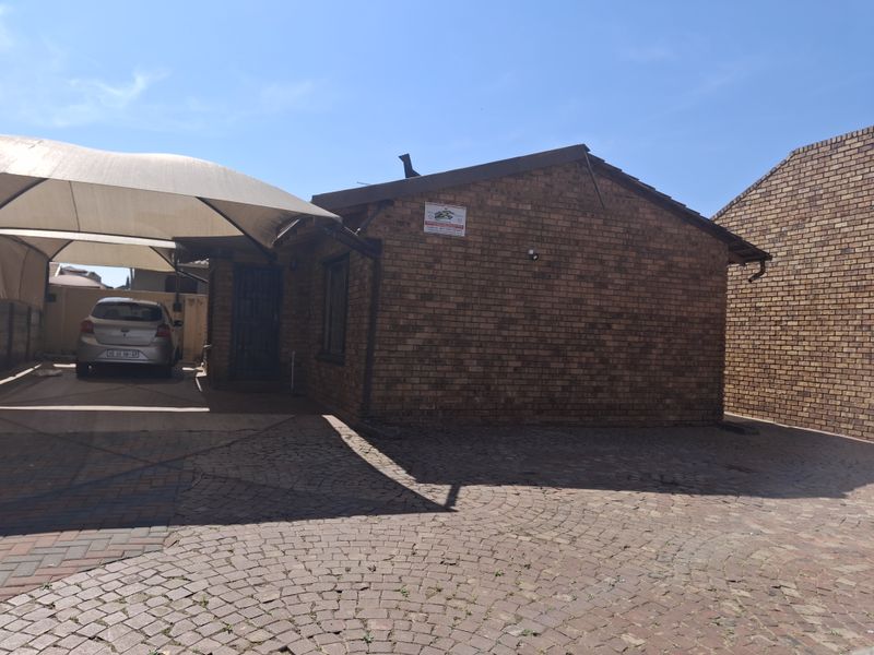 Front exterior view of a face brick house featuring a paved driveway and a shade cloth carport.