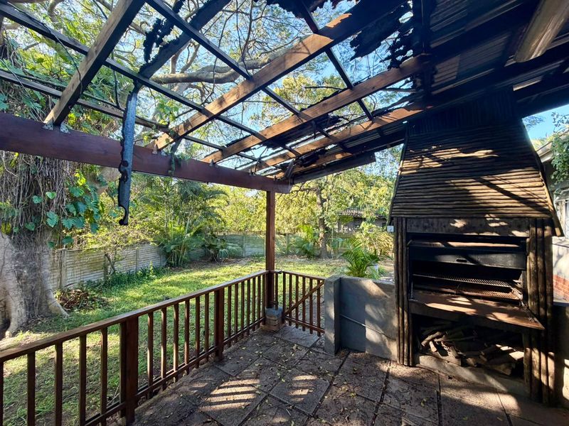 Outdoor patio area featuring a built-in braai and timber pergola structure in need of repair and maintenance.