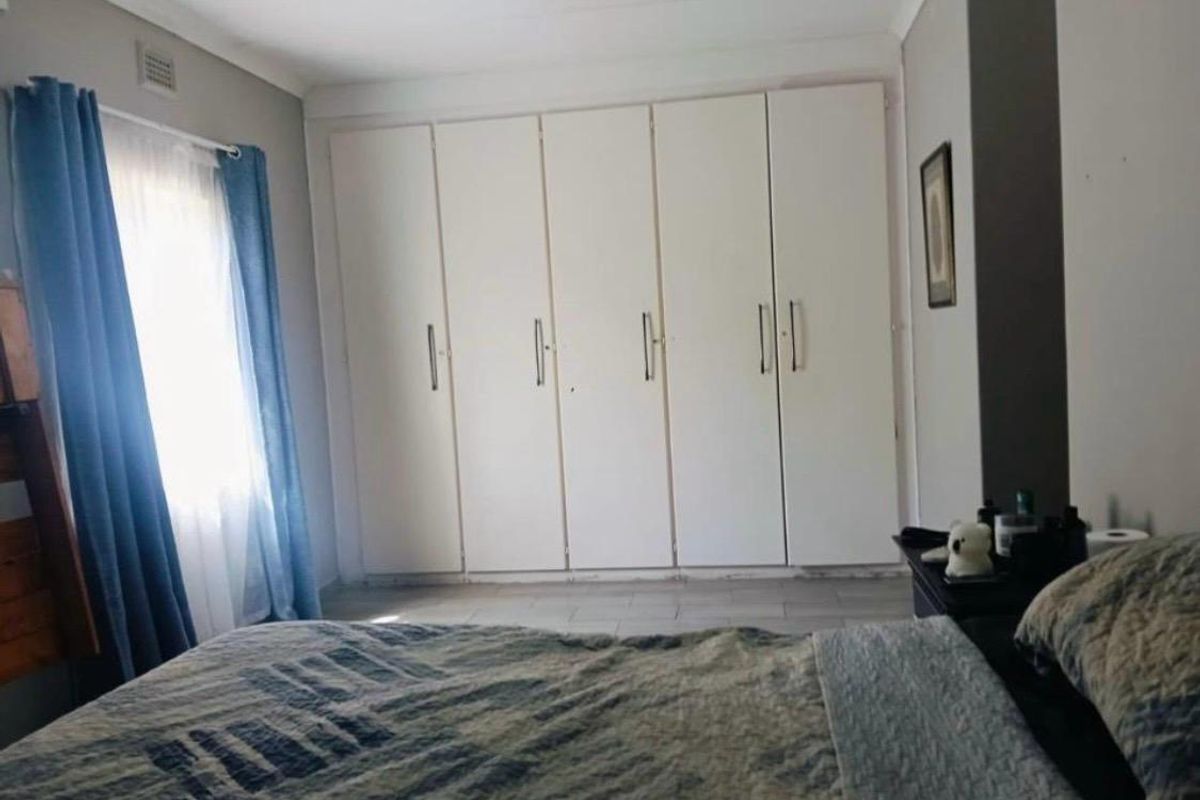 A bedroom featuring built-in cupboards and tiled flooring, offering a functional space with neutral wall finishes.