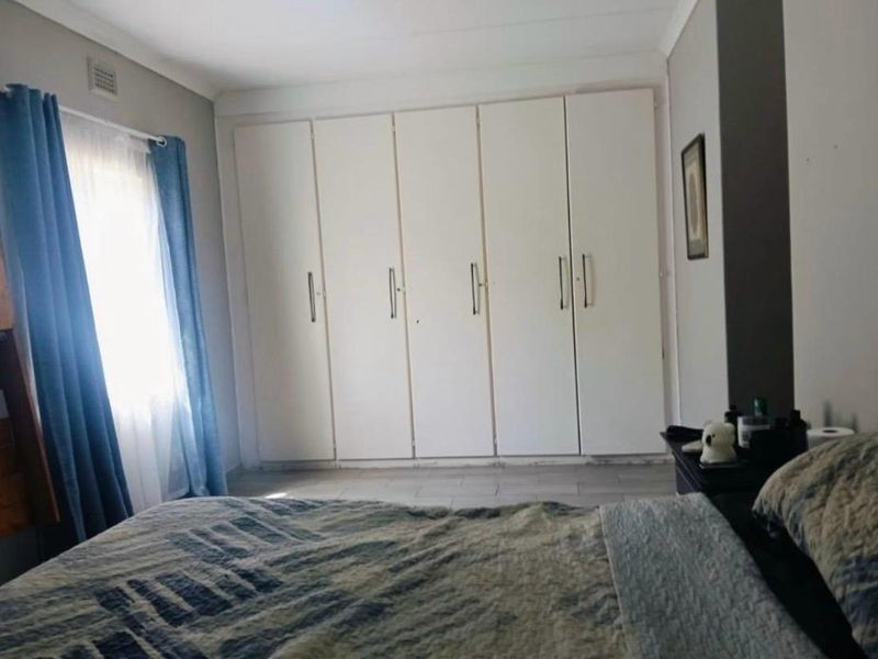 A bedroom featuring built-in cupboards and tiled flooring, offering a functional space with neutral wall finishes.