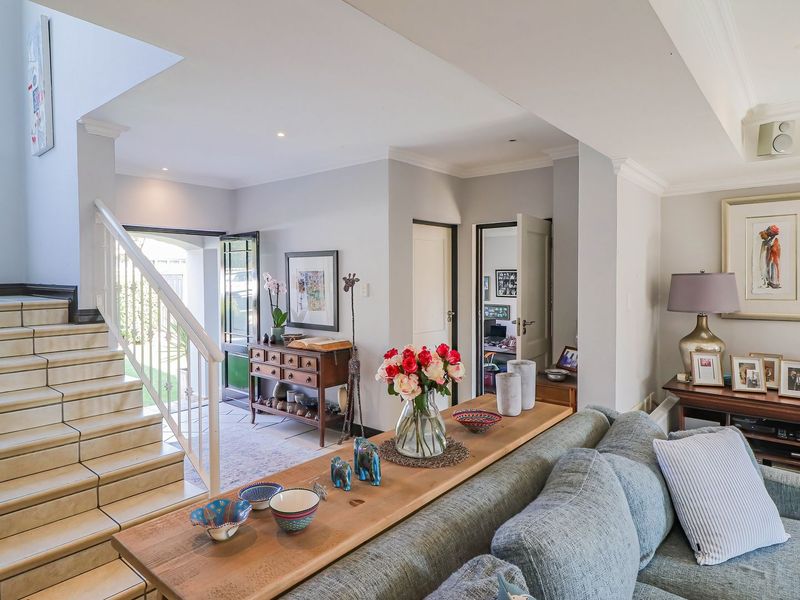 Spacious living area featuring a tiled staircase with metal balustrade, recessed lighting, and crown molding, creating a bright and welcoming open-plan atmosphere.