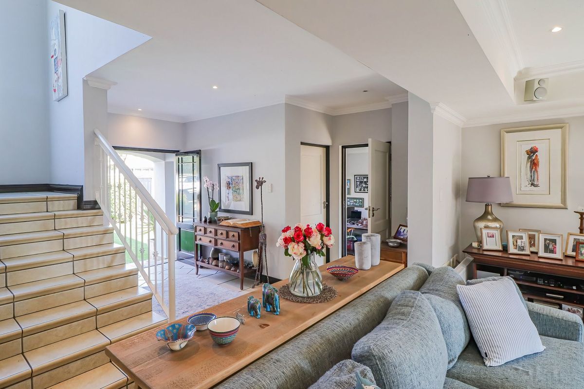 Spacious living area featuring a tiled staircase with metal balustrade, recessed lighting, and crown molding, creating a bright and welcoming open-plan atmosphere.