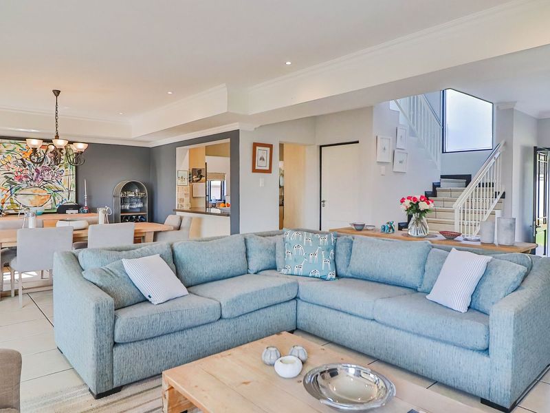 Spacious open-plan living and dining area featuring tiled floors, recessed lighting, and a staircase leading to the upper level.