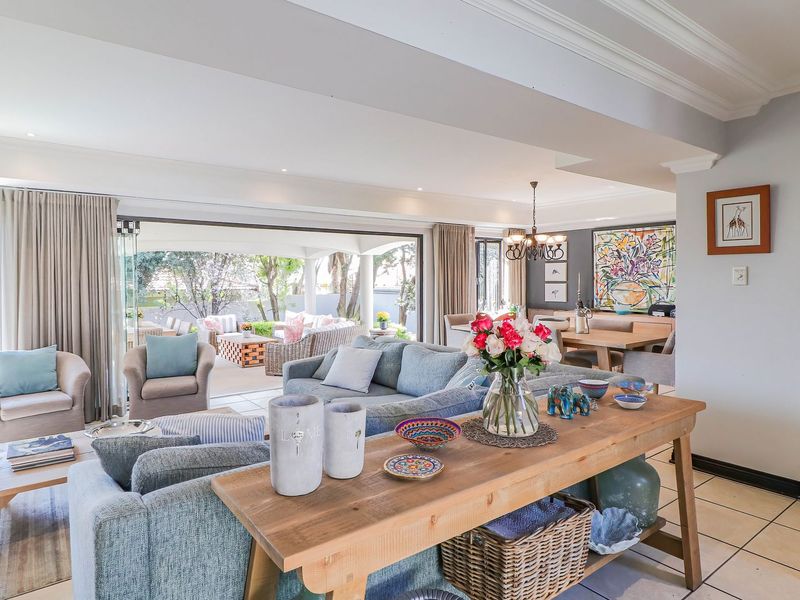 Spacious open-plan living and dining area featuring tiled floors, crown molding, and large sliding doors that provide seamless access to the outdoor patio.