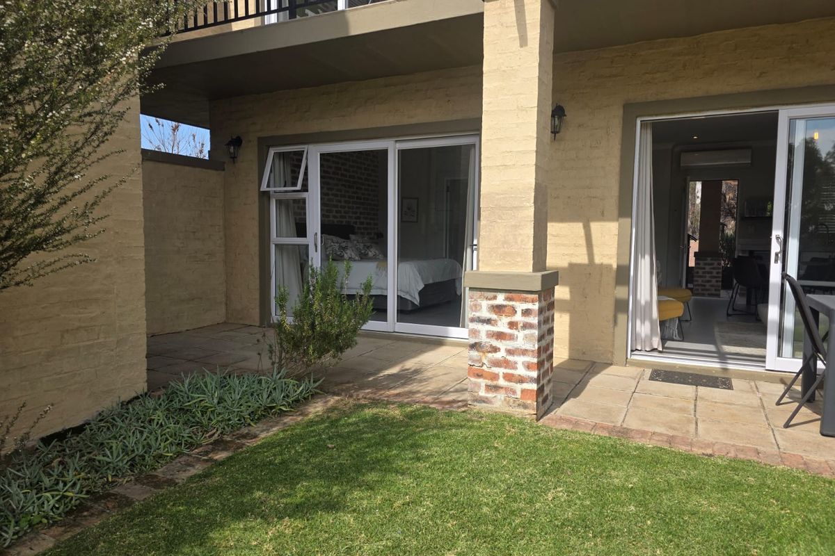Rear view of the flat featuring a paved patio area, brick pillar detailing, and sliding glass doors providing access to the interior living spaces.
