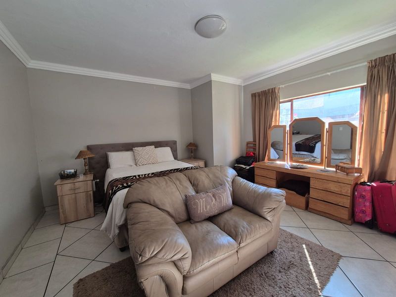 Spacious bedroom featuring tiled flooring, crown molding, and a large window allowing for natural light.