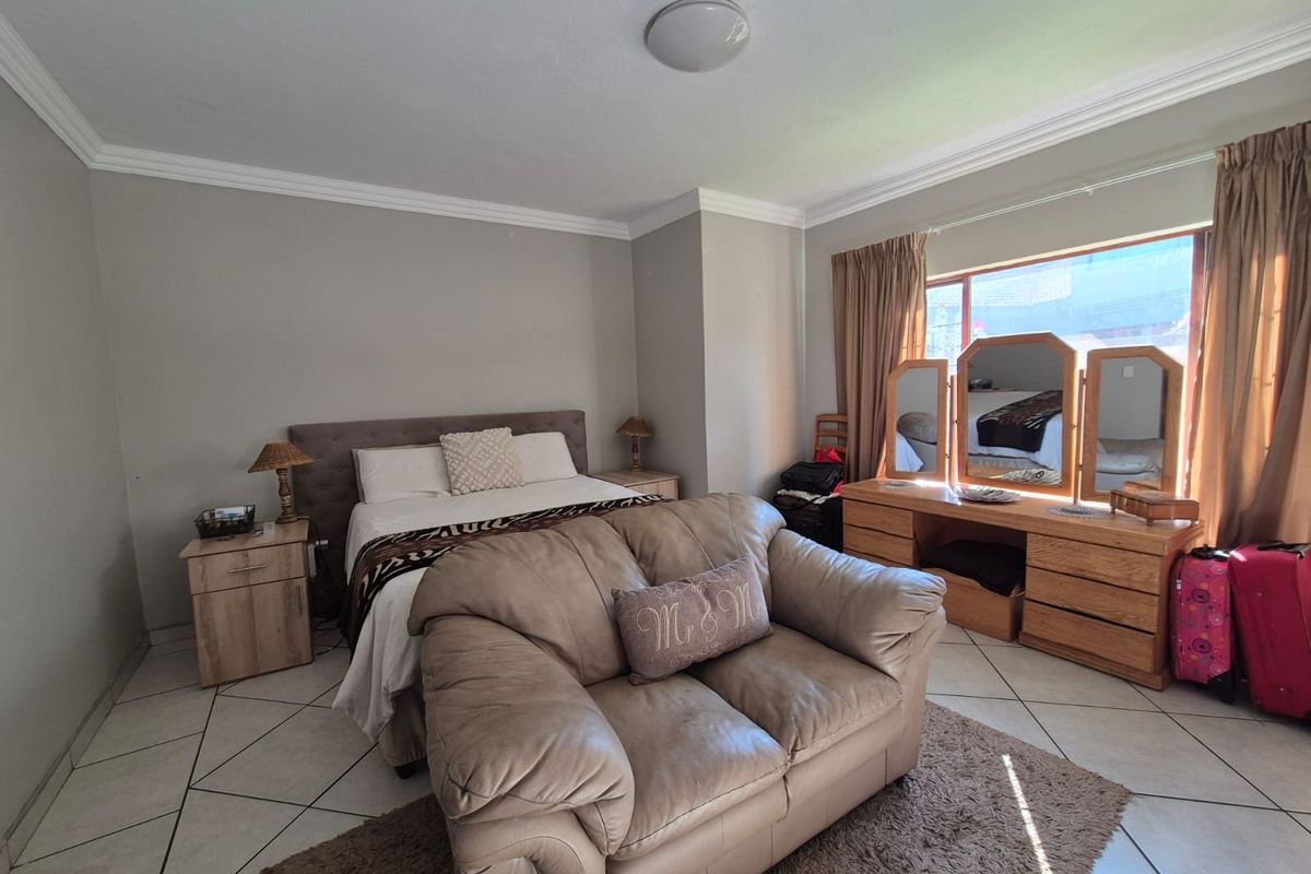 Spacious bedroom featuring tiled flooring, crown molding, and a large window allowing for natural light.