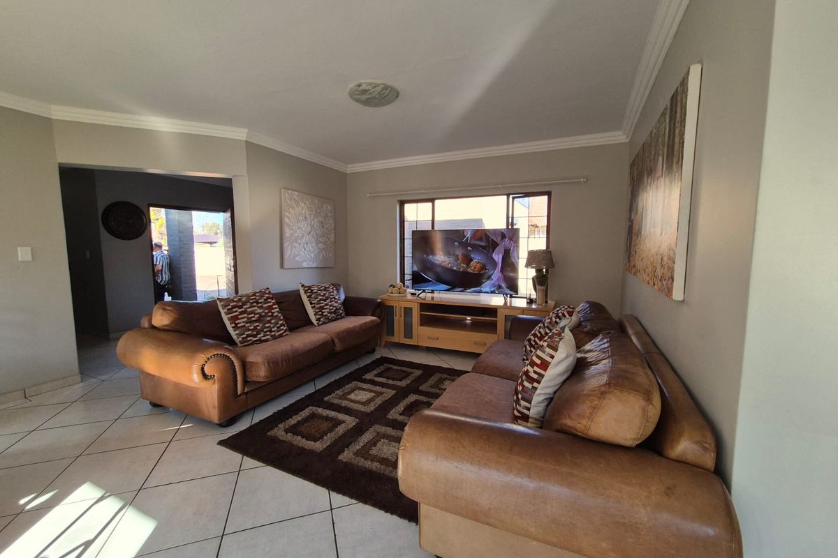 A comfortable living room featuring tiled flooring, crown molding, and natural light from the window, providing a functional and inviting space.
