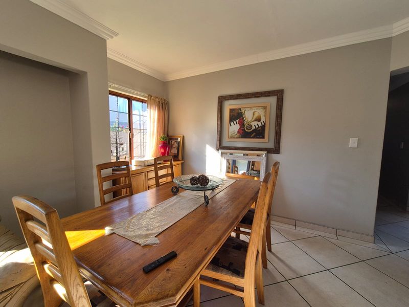A dining room featuring tiled flooring, crown molding, and natural light from a window.