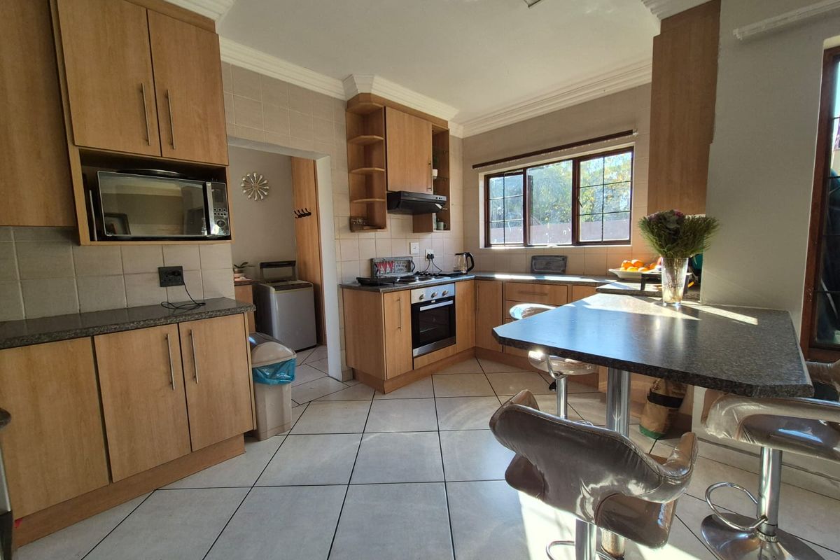 A functional kitchen featuring wood-finish cabinetry, built-in appliances, tiled flooring, and an integrated breakfast nook, offering a practical layout for daily use.