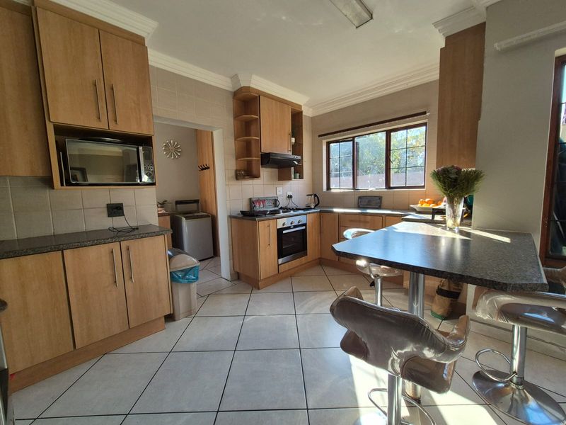 A functional kitchen featuring wood-finish cabinetry, built-in appliances, tiled flooring, and an integrated breakfast nook, offering a practical layout for daily use.