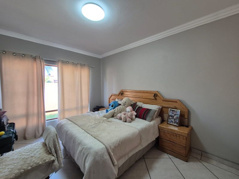 A bedroom featuring tiled flooring, crown molding, and a built-in wooden headboard with integrated bedside tables.