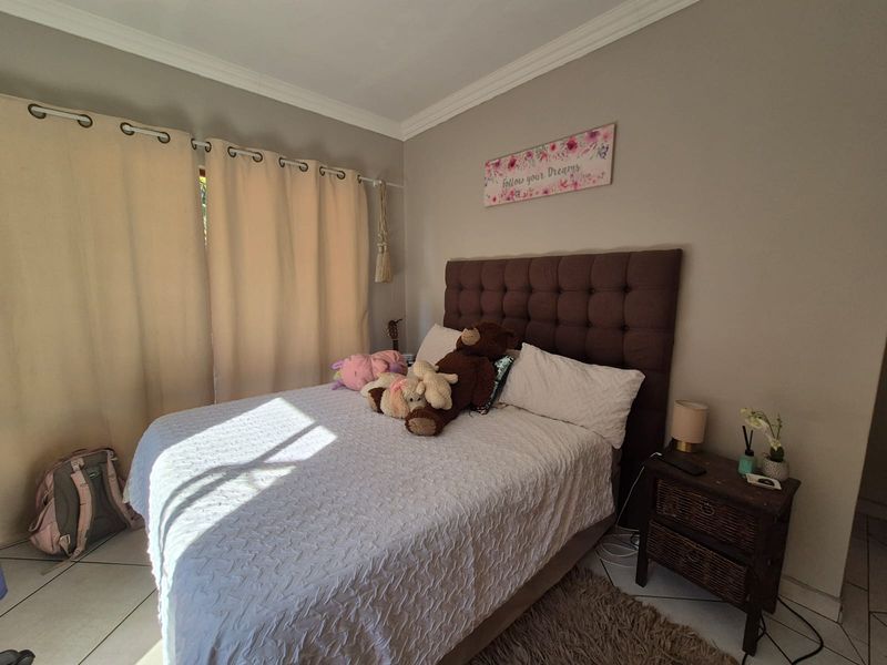 A bedroom featuring neutral wall tones, crown molding, and tiled flooring, providing a functional and comfortable living space.