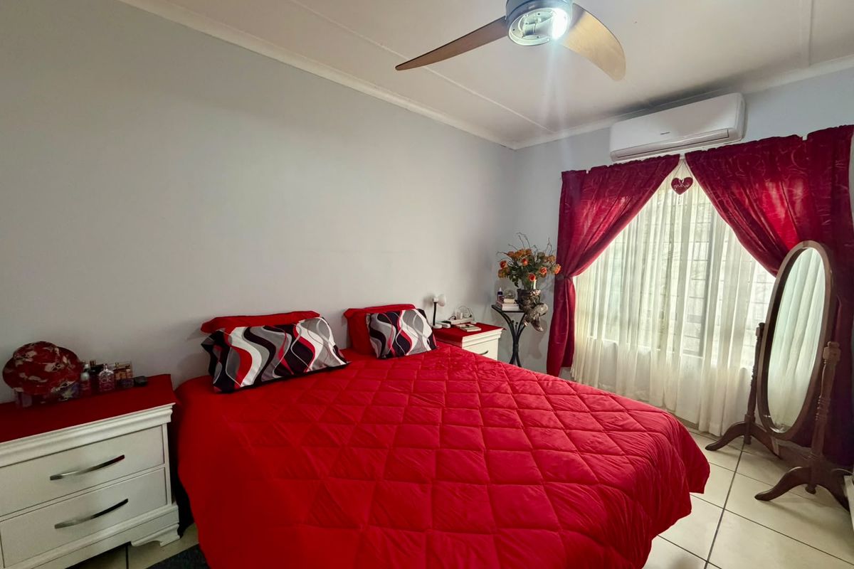 A bedroom featuring tiled flooring, a ceiling fan, and a wall-mounted split-system air conditioner.
