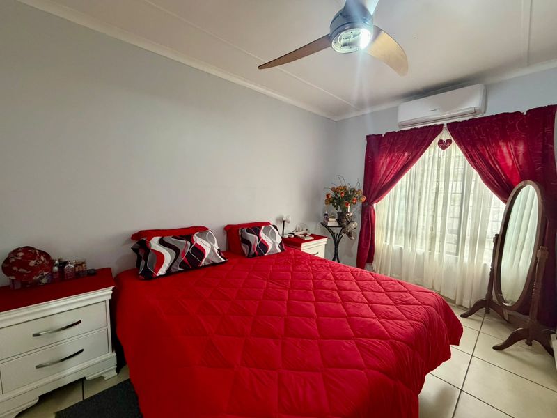 A bedroom featuring tiled flooring, a ceiling fan, and a wall-mounted split-system air conditioner.