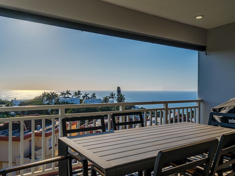 A covered balcony featuring a protective railing and recessed lighting, offering expansive ocean views.