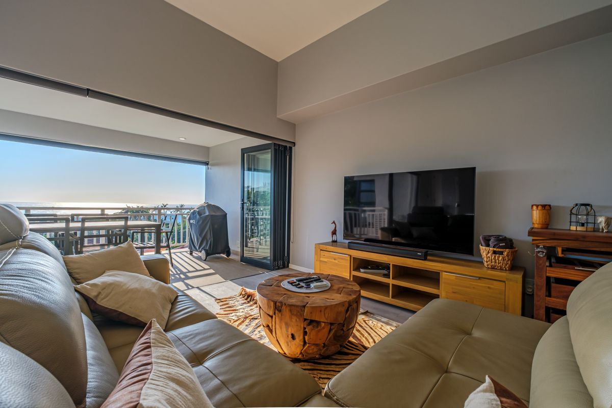 A bright living room featuring large bi-fold doors that open onto a balcony with ocean views, creating a seamless indoor-outdoor flow.