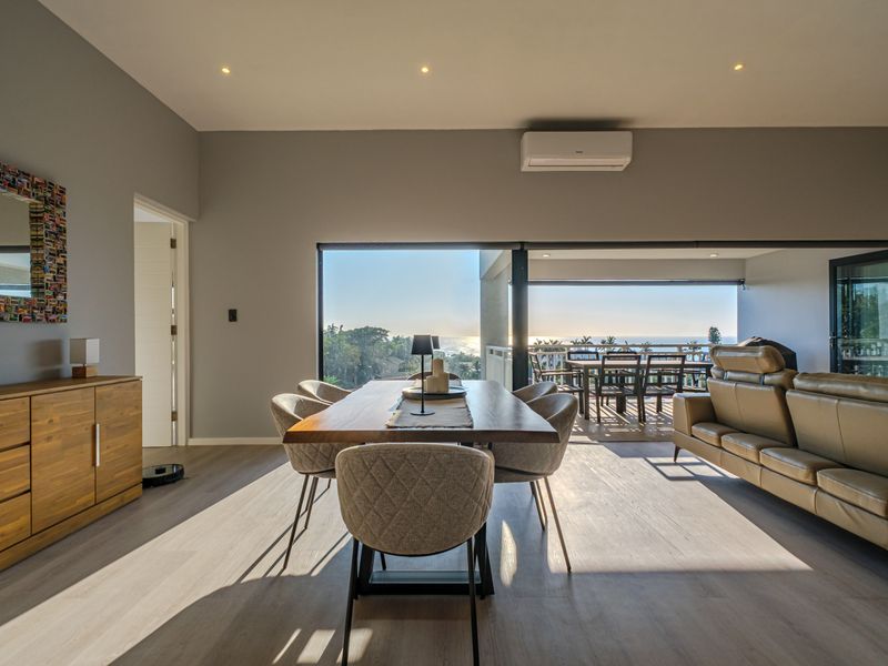 Spacious open-plan living and dining area featuring modern laminate flooring, recessed lighting, and large sliding doors opening to a scenic balcony.