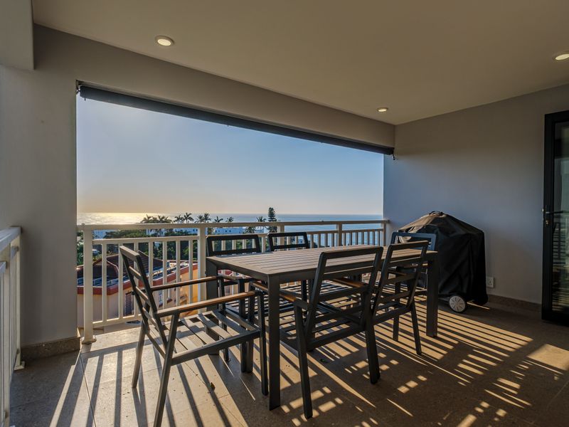 Spacious covered balcony featuring tiled flooring, recessed lighting, and a metal balustrade, offering expansive ocean views.