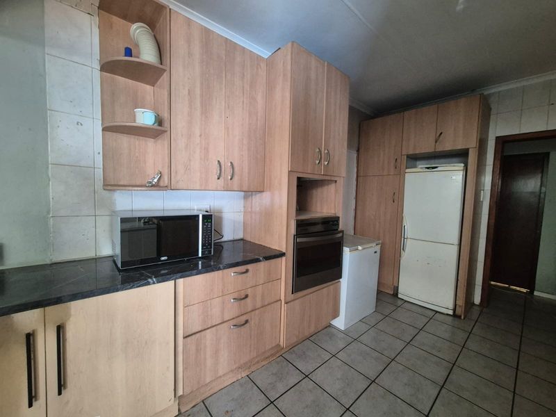 A functional kitchen featuring light wood-tone cabinetry, built-in oven, tiled backsplash, and tiled flooring, offering a dated aesthetic ready for modernization.