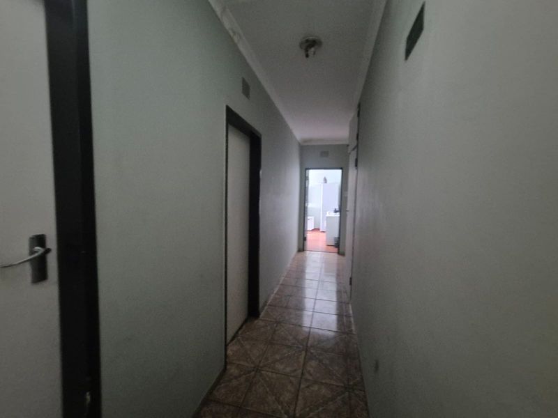A narrow interior hallway featuring tiled flooring and neutral wall finishes, providing access to adjacent rooms within the property.