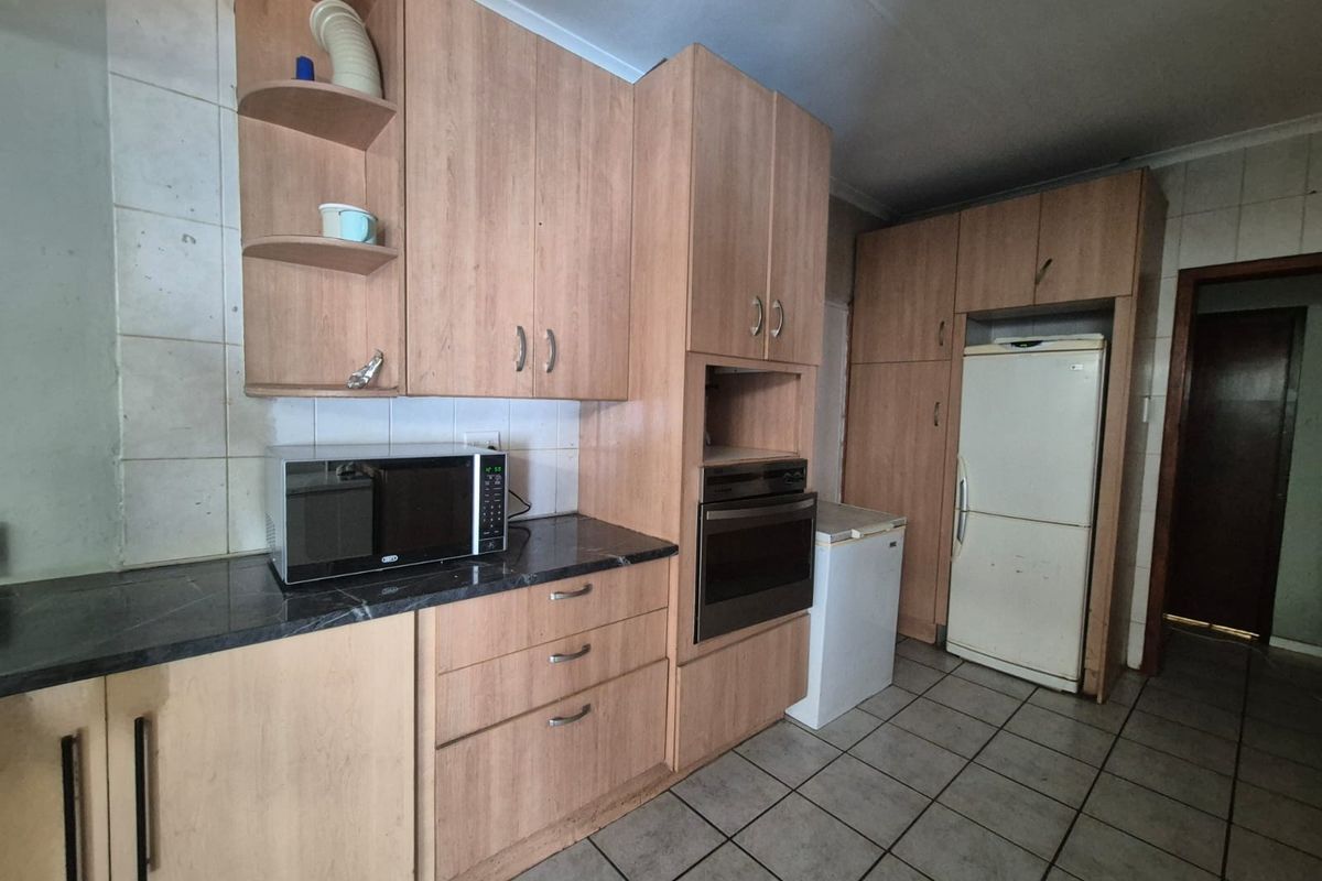 A functional kitchen featuring light wood-tone cabinetry, built-in oven, tiled backsplash, and tiled flooring, offering a dated aesthetic ready for modernization.