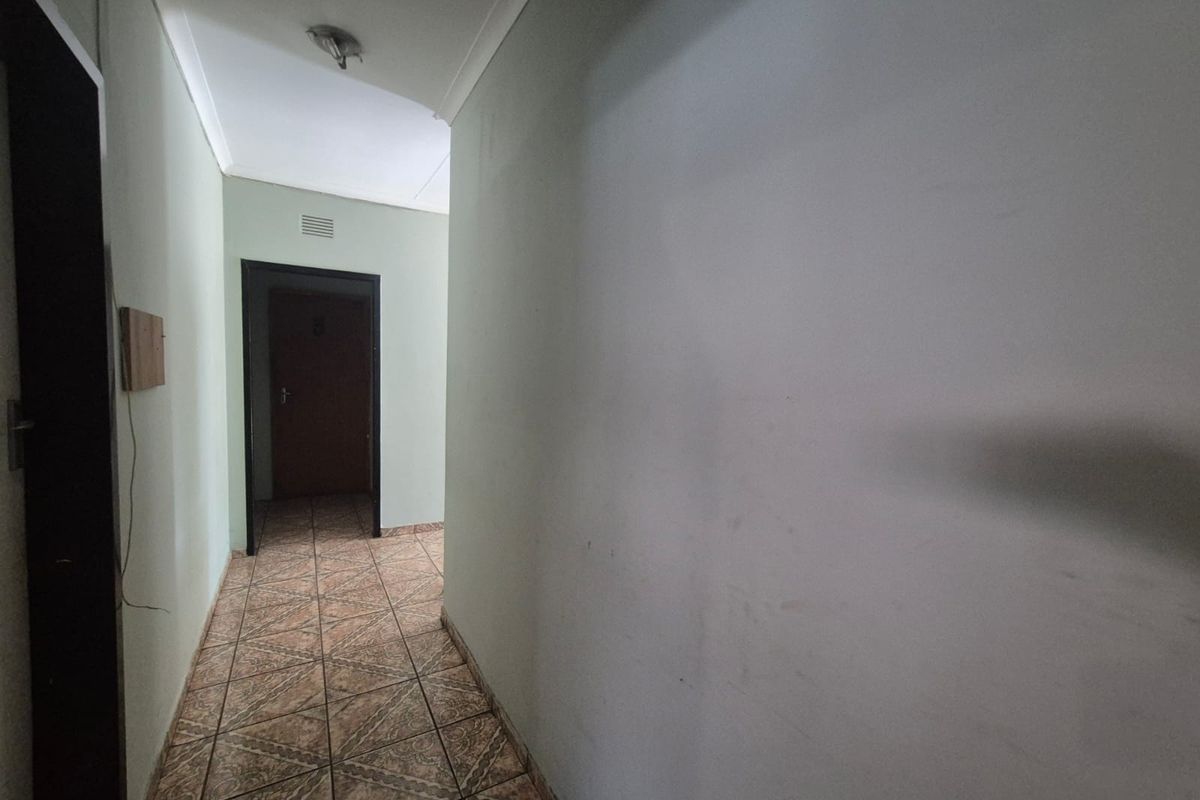 A vacant interior hallway featuring tiled flooring and neutral wall finishes, providing access to adjacent rooms.
