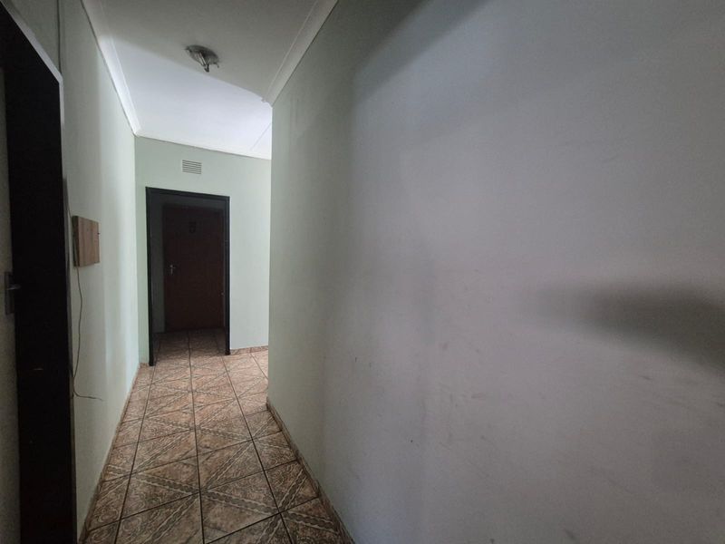 A vacant interior hallway featuring tiled flooring and neutral wall finishes, providing access to adjacent rooms.