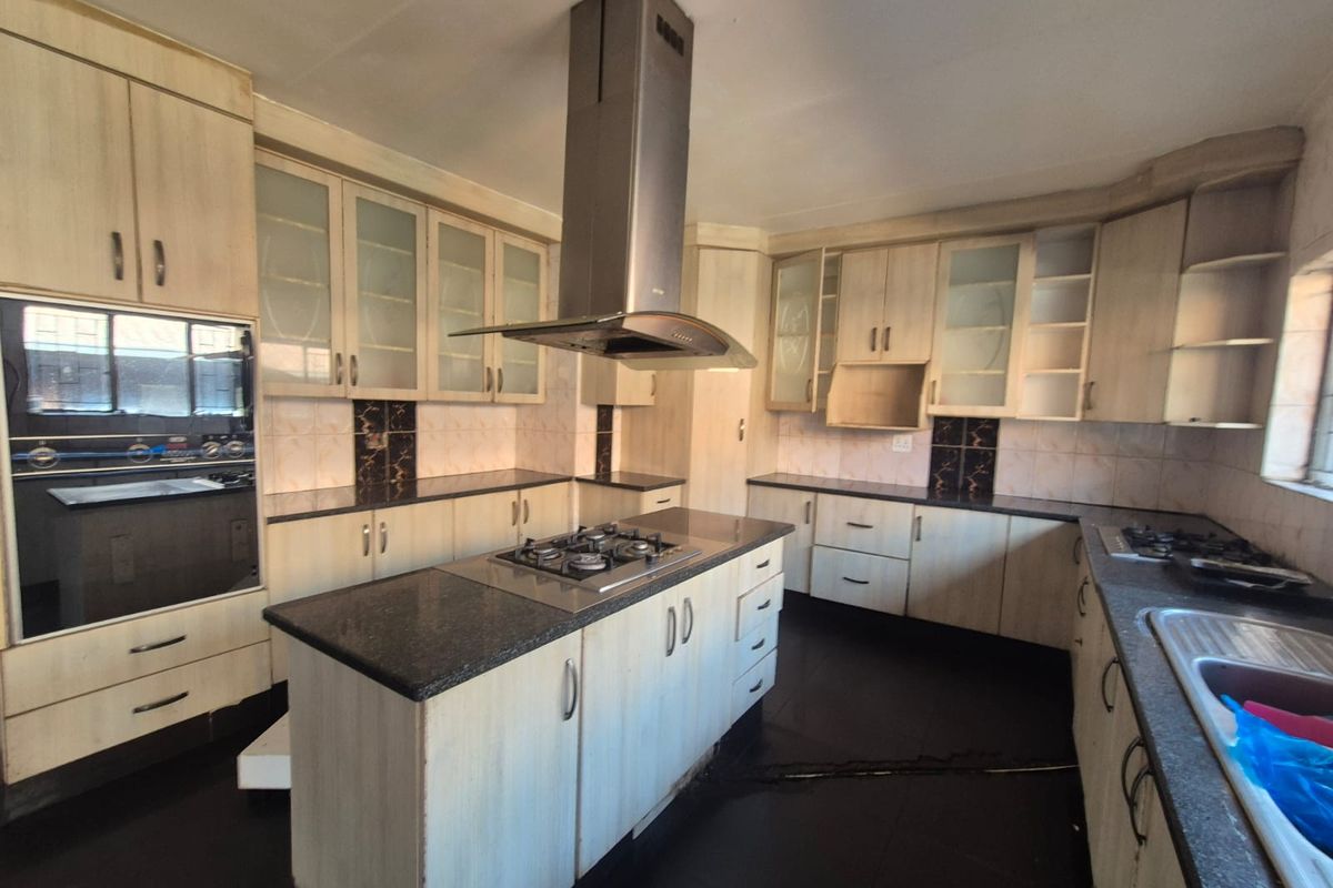 Spacious kitchen featuring a central island with gas hob, extractor fan, built-in oven, ample cabinetry, and granite countertops.