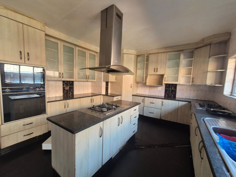 Spacious kitchen featuring a central island with gas hob, extractor fan, built-in oven, ample cabinetry, and granite countertops.