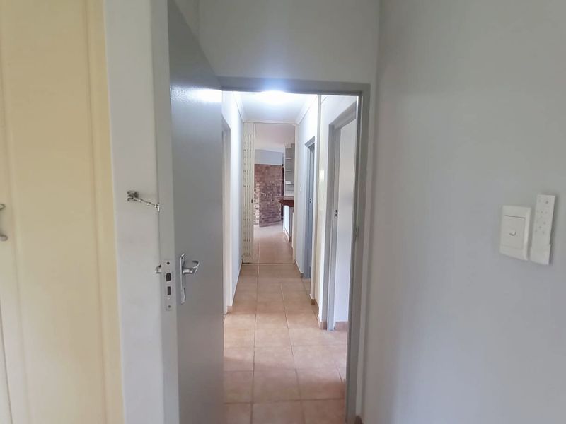 A functional hallway featuring tiled flooring and neutral wall finishes, providing access to multiple rooms within the property.