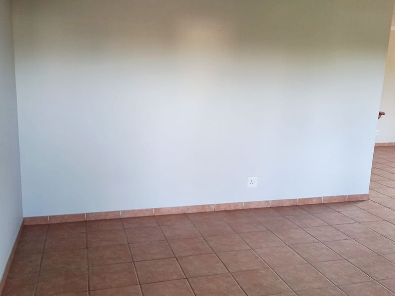 An empty living area featuring neutral painted walls and durable ceramic floor tiles with matching skirting boards.