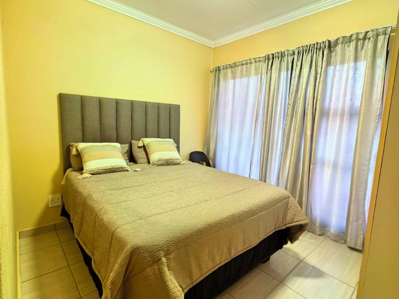 A functional bedroom featuring tiled flooring, ceiling cornice detailing, and a sliding glass door providing natural light.