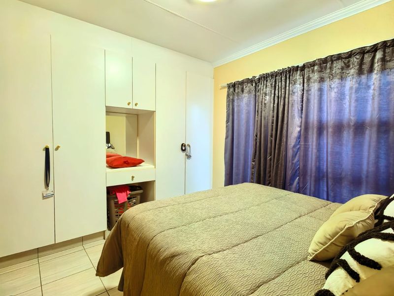 A bedroom featuring built-in cupboards with a central vanity area, tiled flooring, and a ceiling light fixture.