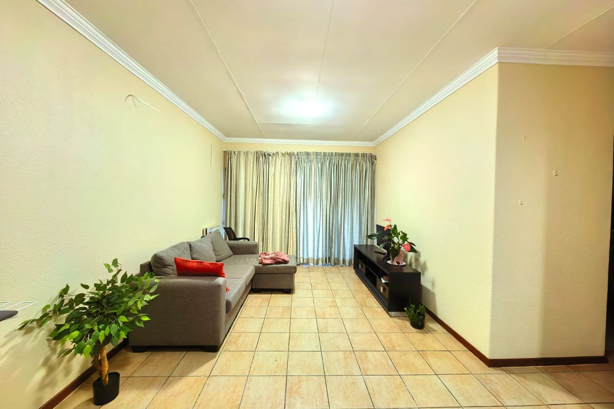 A living room featuring tiled flooring and ceiling cornicing, offering a neutral base ready for modern updates and personal styling.