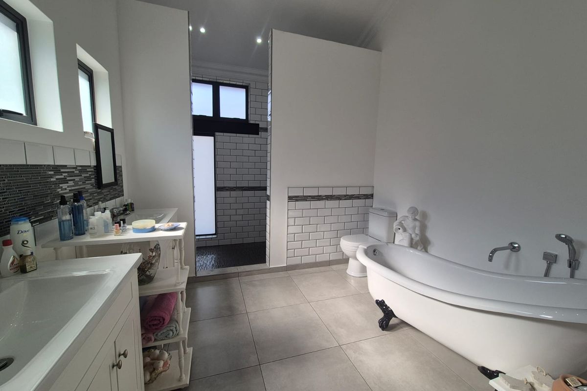 Spacious modern bathroom featuring a freestanding clawfoot bathtub, separate walk-in shower, dual vanity, and contemporary subway tile accents.