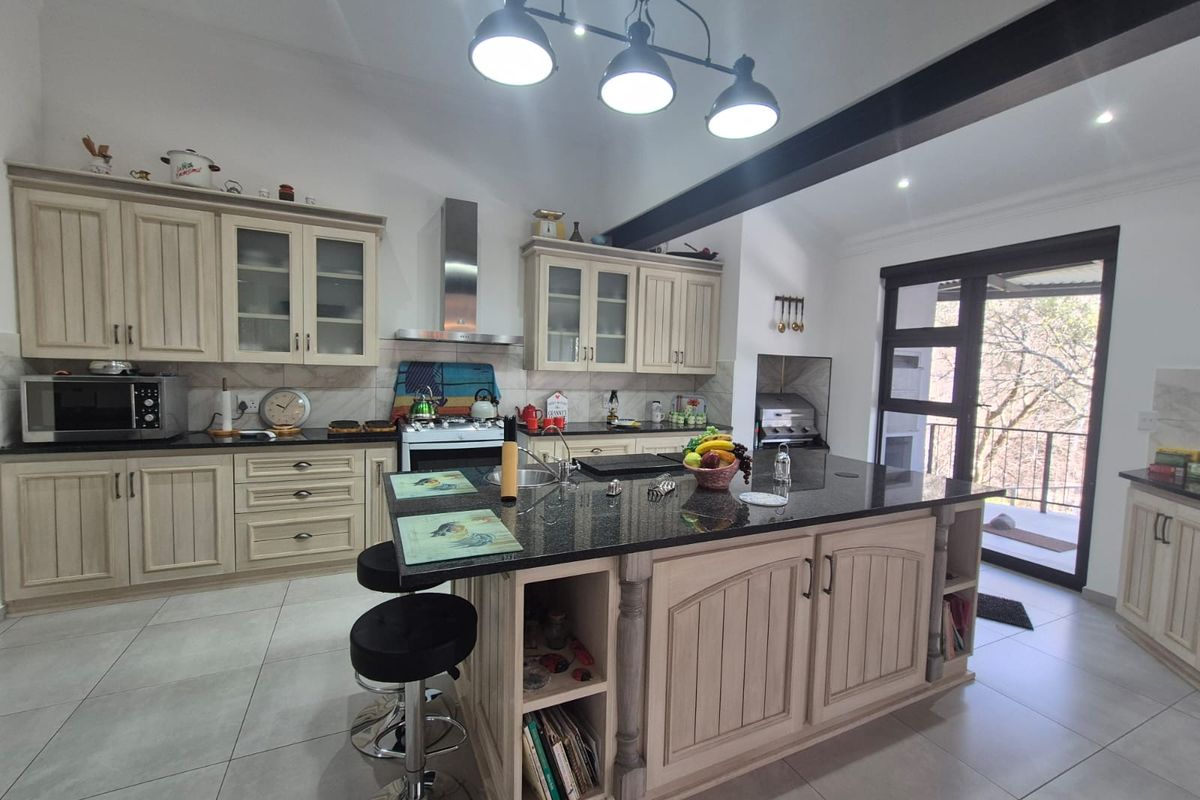 Spacious kitchen featuring a large central island with granite countertops, ample cabinetry, modern appliances, and direct access to an outdoor balcony area.