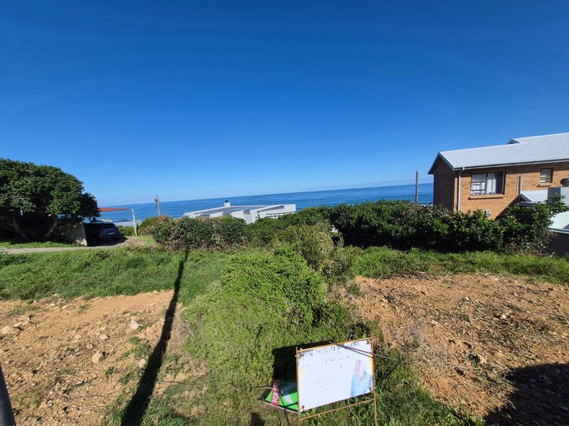 A vacant residential plot offering expansive ocean views, situated in a coastal neighborhood with established surrounding properties.