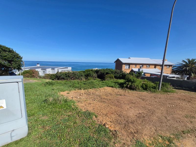A vacant residential plot offering expansive ocean views, featuring existing electrical infrastructure and a street light pole on site.
