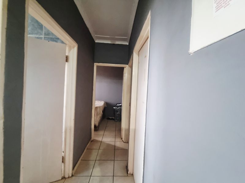 A narrow interior hallway featuring tiled flooring and dark grey painted walls, providing access to adjacent rooms.