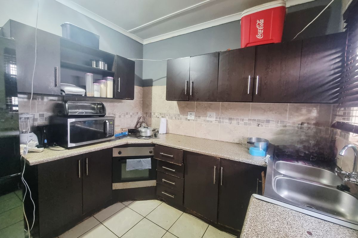 A functional kitchen featuring dark built-in cabinetry, laminate countertops, a built-in oven, and a double bowl sink with tiled backsplash.