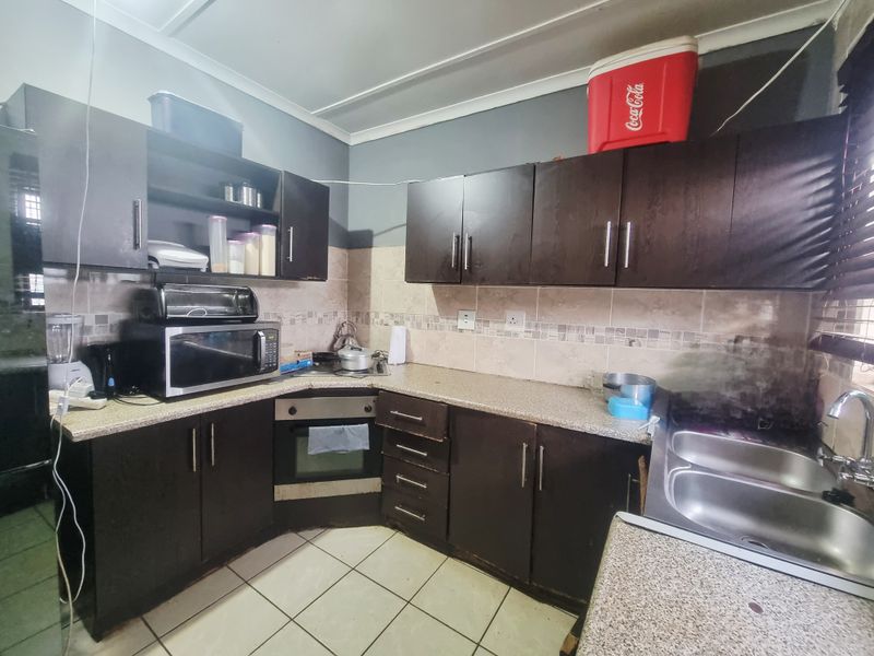 A functional kitchen featuring dark built-in cabinetry, laminate countertops, a built-in oven, and a double bowl sink with tiled backsplash.