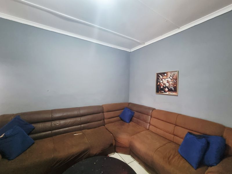 A living room area featuring tiled flooring and coved ceiling details, providing a functional space for relaxation.