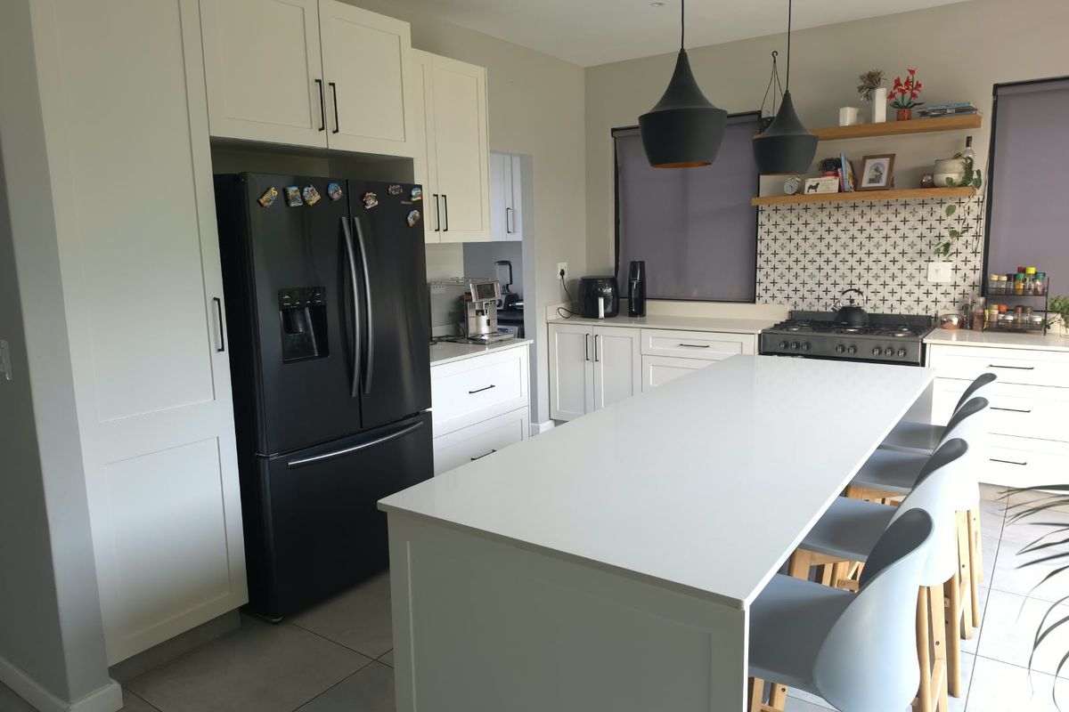 Modern kitchen featuring a central island with quartz countertops, gas cooktop, stylish pendant lighting, and ample built-in cabinetry with a decorative tiled backsplash.