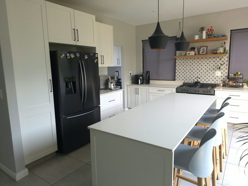 Modern kitchen featuring a central island with quartz countertops, gas cooktop, stylish pendant lighting, and ample built-in cabinetry with a decorative tiled backsplash.