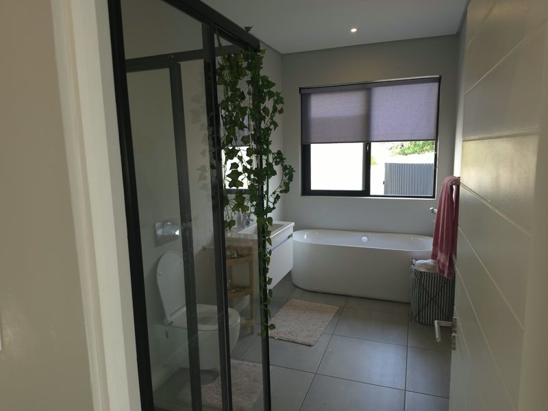 Modern bathroom featuring a freestanding bathtub, wall-hung toilet, vanity cabinet, and a glass-enclosed shower with contemporary tiled finishes.