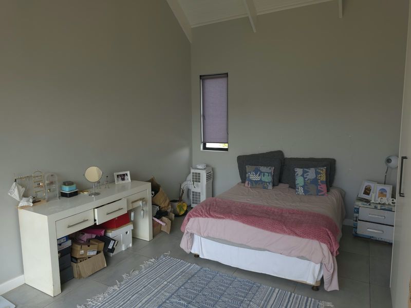 A bedroom featuring tiled flooring and a vaulted ceiling, with visible wall cracks requiring attention.