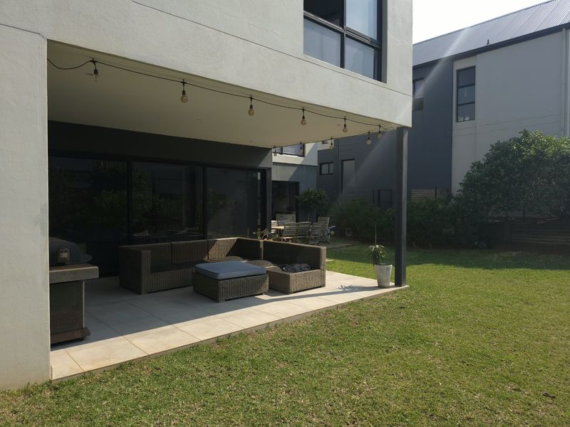 A covered patio area featuring tiled flooring and sliding glass doors, providing seamless indoor-outdoor flow to the rear garden.